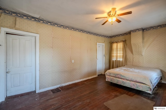 unfurnished bedroom with visible vents, wallpapered walls, ceiling fan, baseboards, and hardwood / wood-style floors