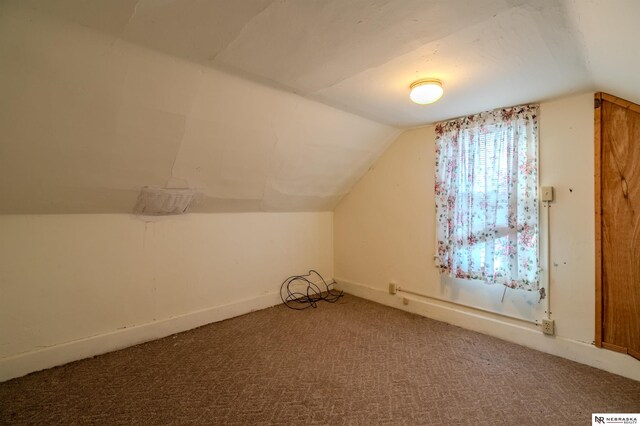 additional living space with baseboards, light carpet, and lofted ceiling