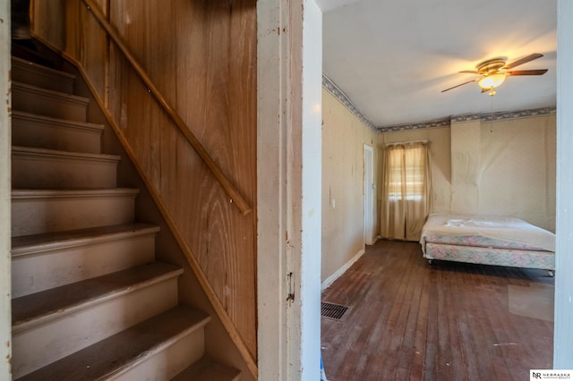 staircase featuring hardwood / wood-style flooring, a ceiling fan, and visible vents