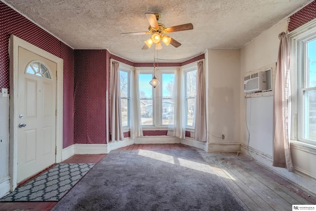 foyer featuring a textured ceiling, an AC wall unit, baseboards, and hardwood / wood-style floors