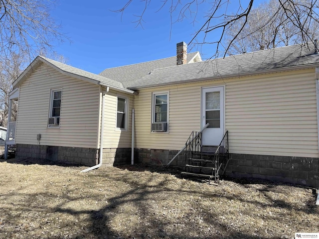 back of house featuring a shingled roof, a chimney, and entry steps