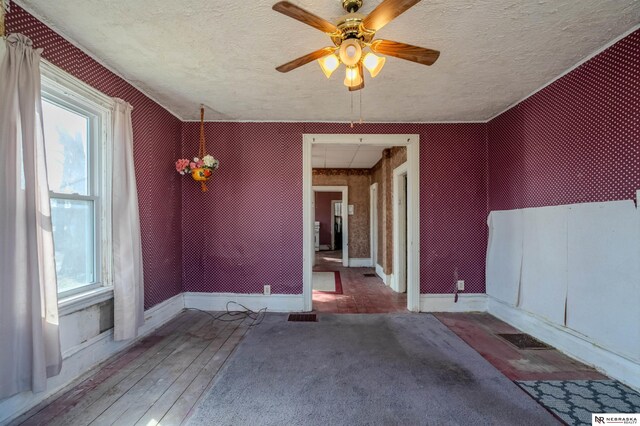 spare room with visible vents, a ceiling fan, a textured ceiling, hardwood / wood-style floors, and baseboards