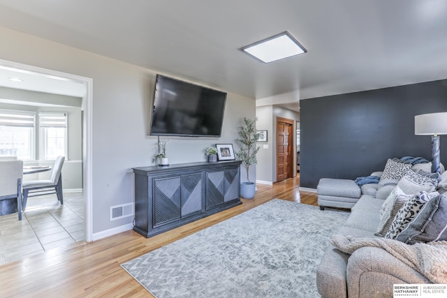 living area featuring visible vents, baseboards, and wood finished floors