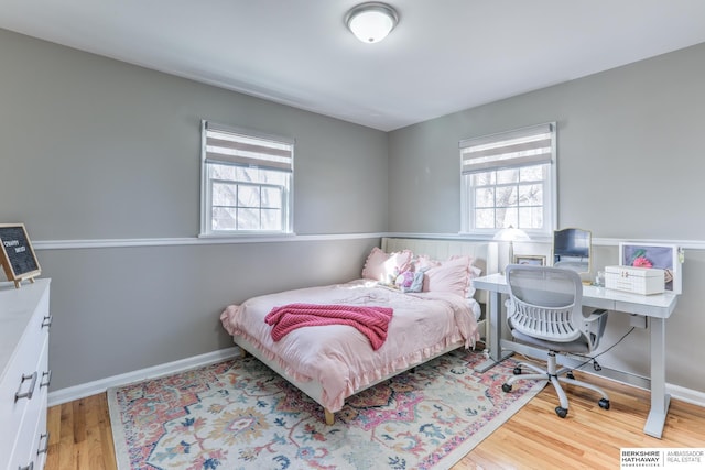 bedroom featuring baseboards, multiple windows, and wood finished floors