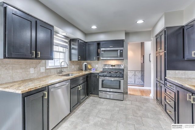 kitchen featuring tasteful backsplash, light stone counters, recessed lighting, appliances with stainless steel finishes, and a sink