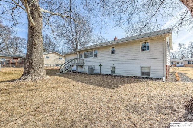 rear view of property with cooling unit, a chimney, and fence