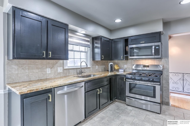 kitchen with a sink, light stone counters, tasteful backsplash, and stainless steel appliances