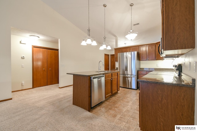 kitchen with a sink, dark countertops, an island with sink, and stainless steel appliances