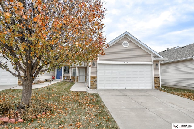 view of front of house featuring a garage, stone siding, and driveway