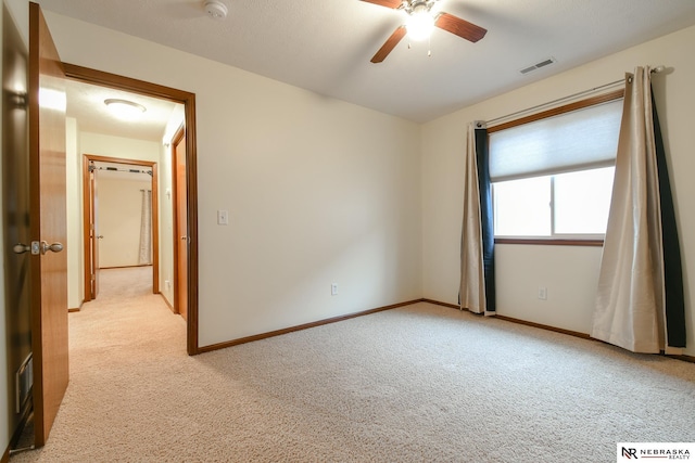 empty room with visible vents, light carpet, baseboards, and ceiling fan