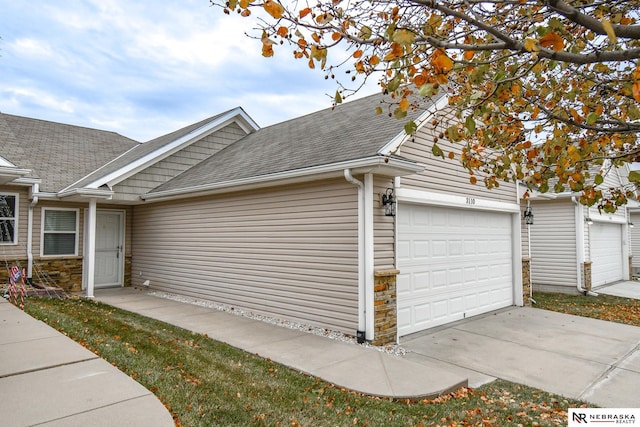 view of property exterior with an attached garage and a shingled roof