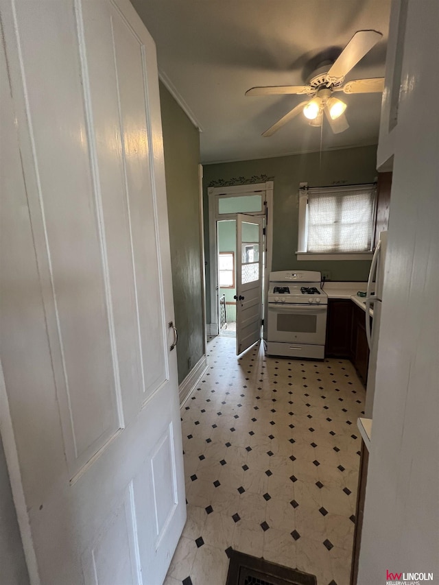 interior space with white appliances, a ceiling fan, light floors, light countertops, and crown molding