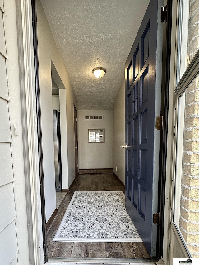 interior space featuring baseboards, wood finished floors, visible vents, and a textured ceiling