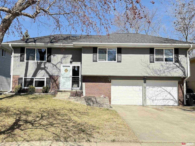 split foyer home with brick siding, driveway, an attached garage, and a front lawn