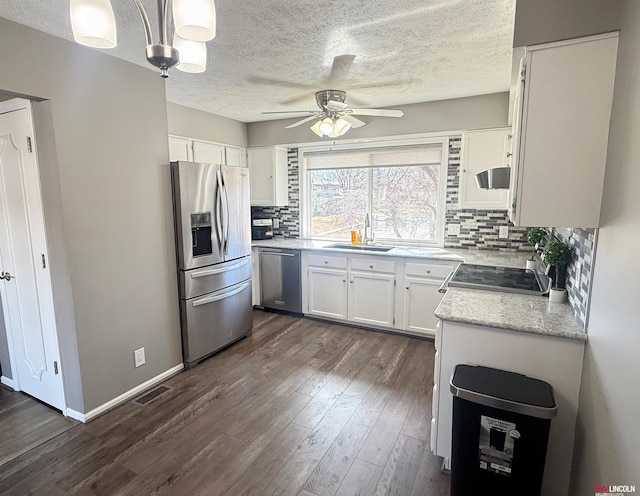 kitchen featuring backsplash, appliances with stainless steel finishes, dark wood-style floors, white cabinets, and a sink