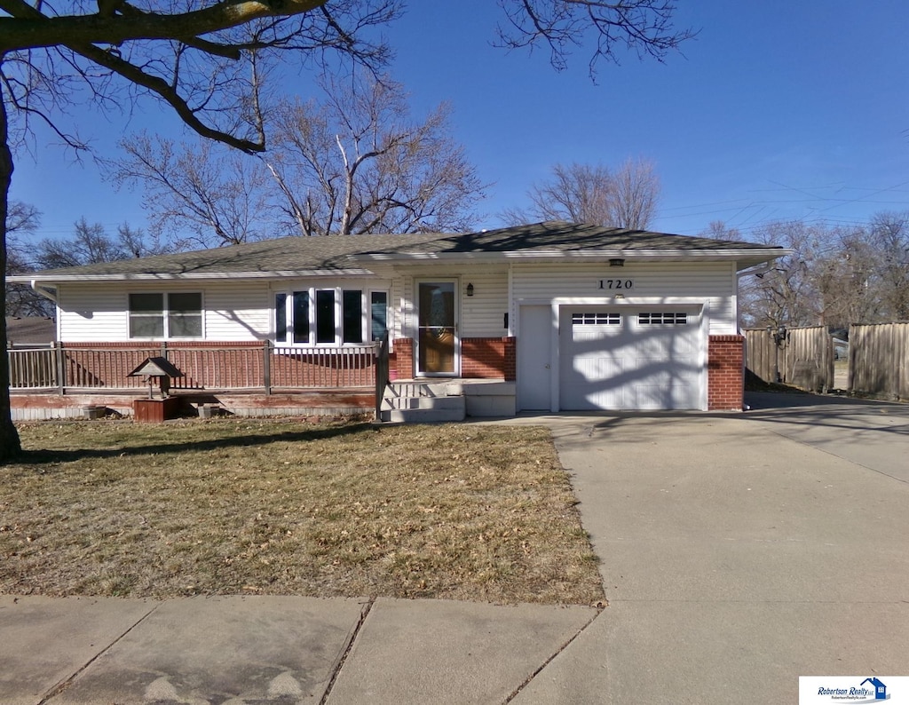 ranch-style home with brick siding, concrete driveway, a garage, and fence