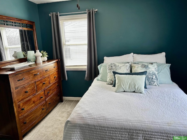 bedroom with light carpet, multiple windows, and baseboards