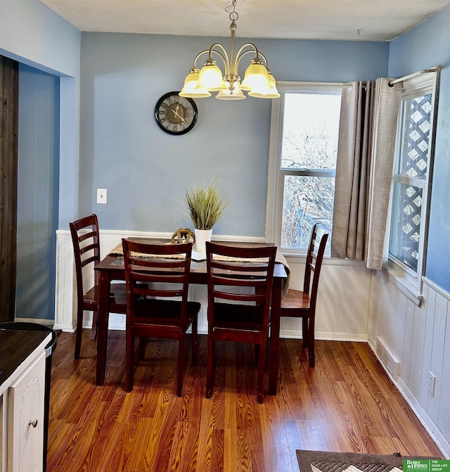 dining area with a notable chandelier, visible vents, and wood finished floors