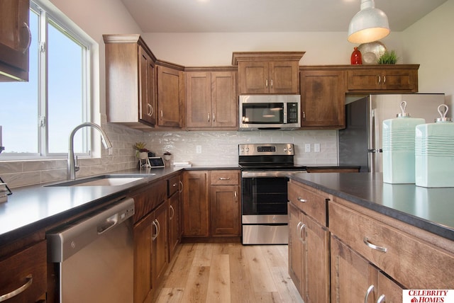 kitchen with decorative backsplash, light wood-style flooring, stainless steel appliances, and a sink