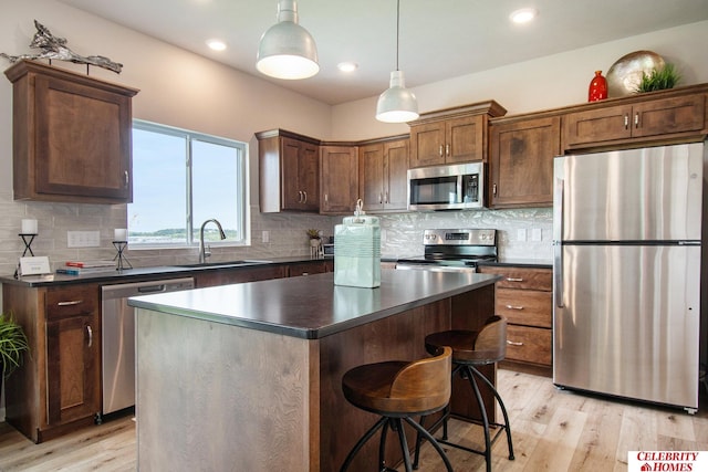 kitchen featuring dark countertops, light wood-style flooring, appliances with stainless steel finishes, and a sink