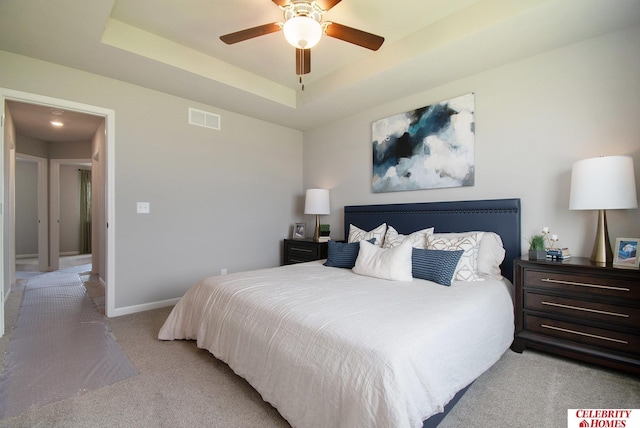 bedroom with visible vents, ceiling fan, baseboards, light carpet, and a raised ceiling