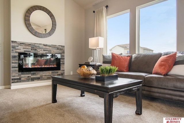 living room with a stone fireplace, baseboards, and carpet floors