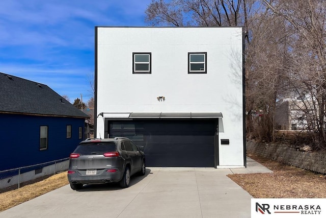 garage featuring concrete driveway and fence