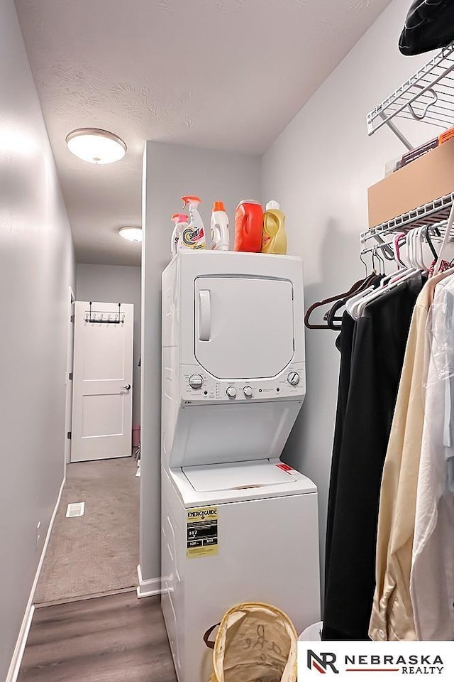 laundry room with laundry area, wood finished floors, baseboards, and stacked washer and clothes dryer