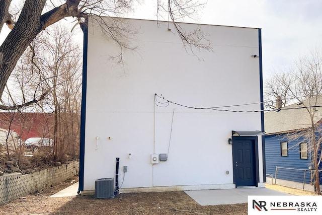 view of side of home featuring fence, central AC, and stucco siding