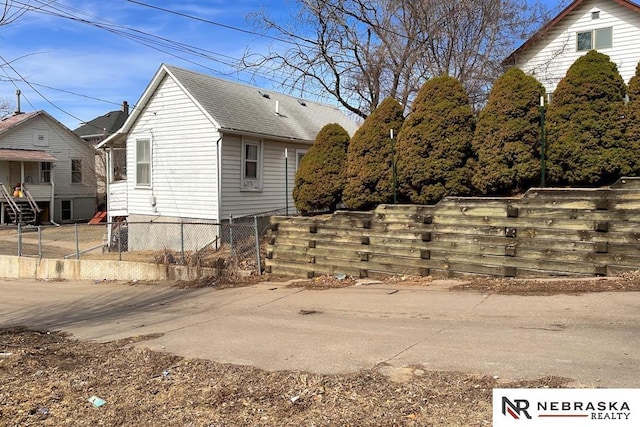 view of property exterior with roof with shingles and fence