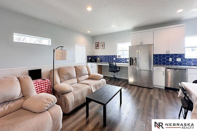 living area featuring dark wood finished floors, recessed lighting, built in desk, and a textured ceiling