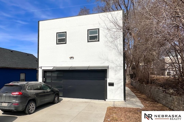 view of front facade with stucco siding, driveway, and a garage