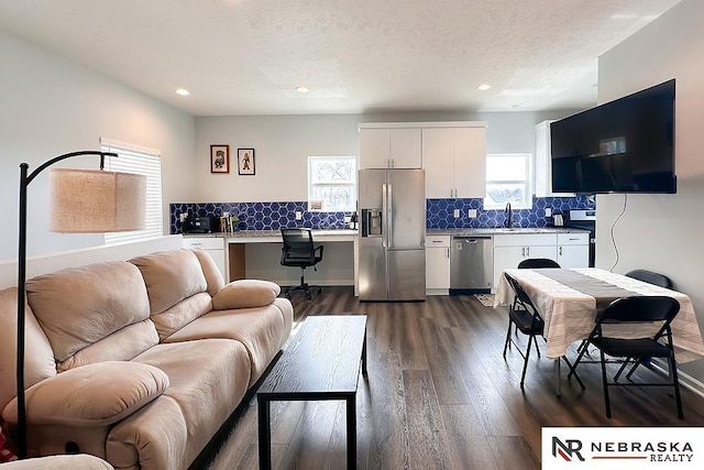 living area with dark wood-type flooring, recessed lighting, built in desk, and a textured ceiling