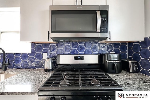 kitchen featuring a sink, tasteful backsplash, appliances with stainless steel finishes, and white cabinetry