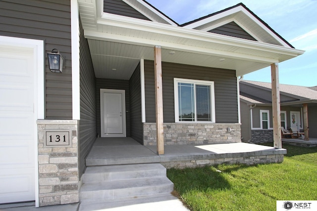 doorway to property featuring a garage, stone siding, and a porch