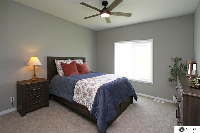 bedroom with a ceiling fan, visible vents, light colored carpet, and baseboards