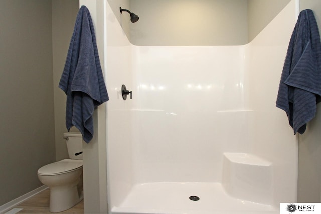 full bathroom with a shower, baseboards, toilet, and wood finished floors