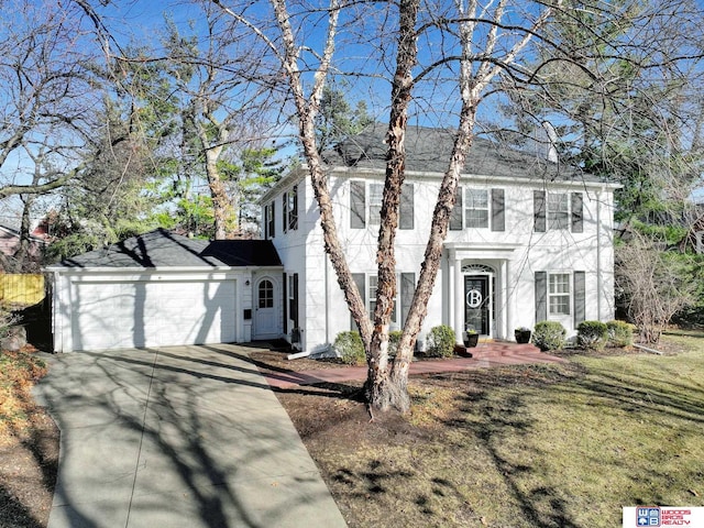 colonial house featuring a front lawn, a garage, driveway, and stucco siding