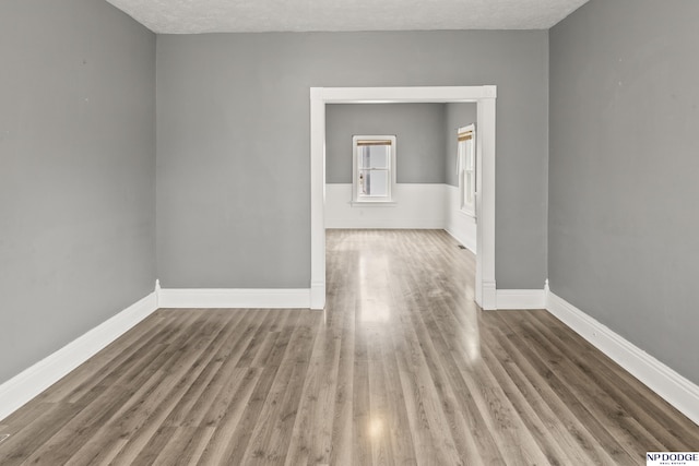 empty room featuring wood finished floors, baseboards, and a textured ceiling