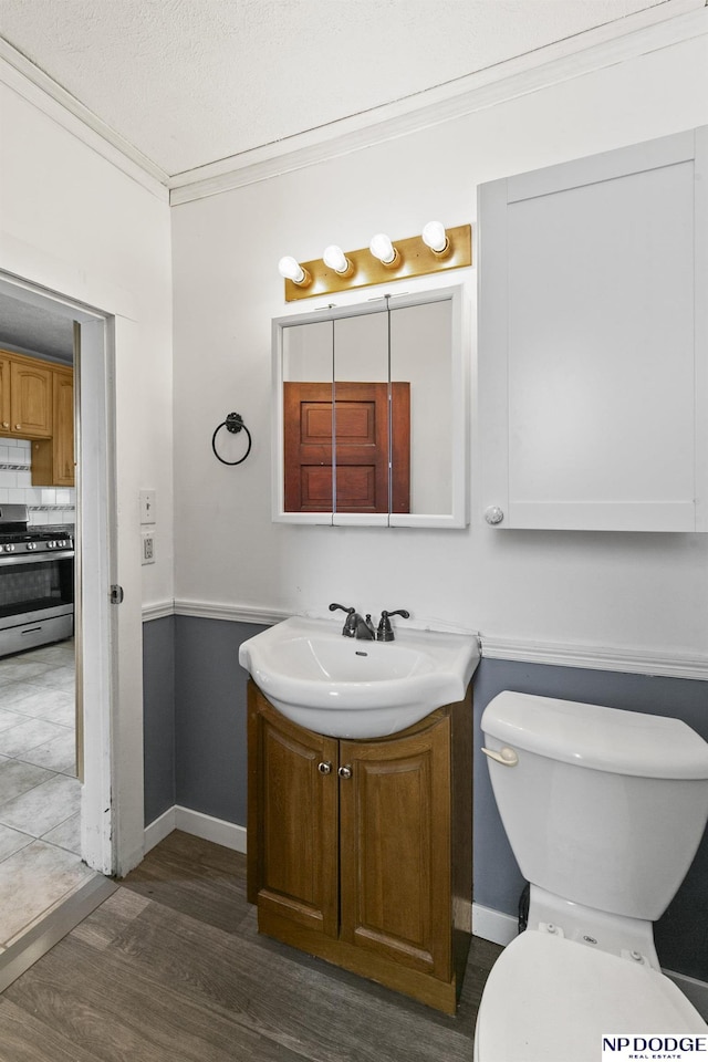 bathroom with backsplash, crown molding, toilet, wood finished floors, and vanity