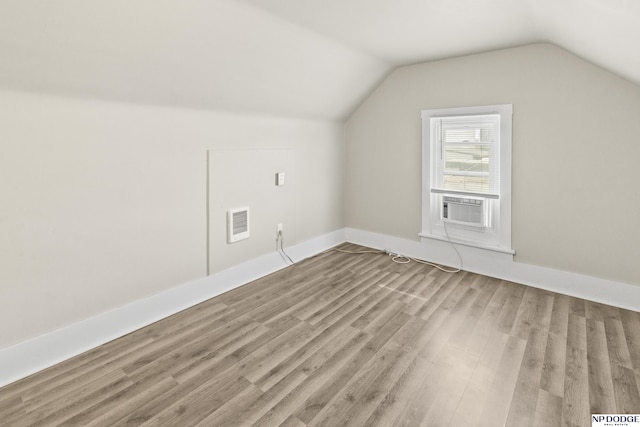 additional living space featuring visible vents, cooling unit, light wood-type flooring, and lofted ceiling