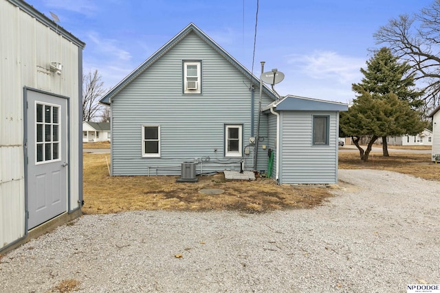 rear view of house with gravel driveway and central AC unit