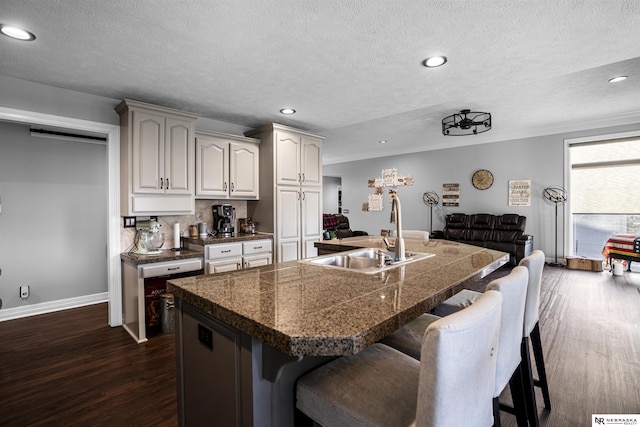 kitchen with dark wood-style flooring, tile countertops, a breakfast bar, and a sink