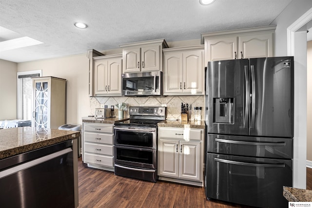 kitchen with dark wood-style flooring, tile counters, appliances with stainless steel finishes, a textured ceiling, and backsplash