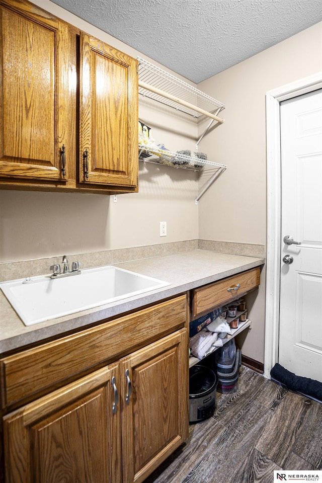 laundry area featuring a textured ceiling, dark wood-type flooring, and a sink