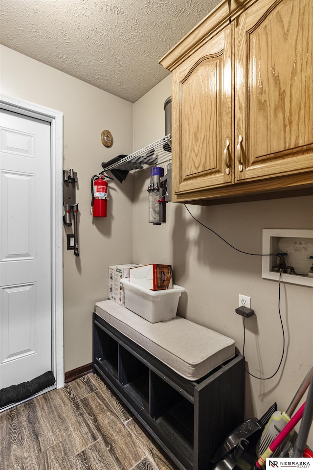 clothes washing area featuring baseboards, dark wood finished floors, washer hookup, cabinet space, and a textured ceiling