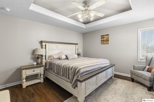 bedroom featuring a ceiling fan, a tray ceiling, baseboards, and dark wood-style flooring