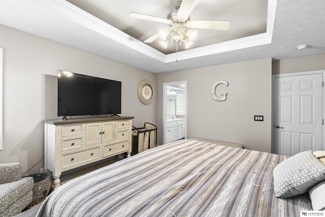 bedroom featuring a ceiling fan, wood finished floors, crown molding, a textured ceiling, and a raised ceiling