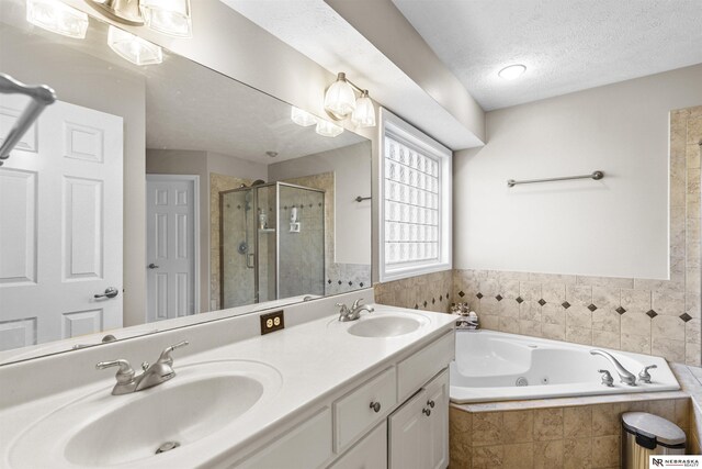 bathroom with a whirlpool tub, a shower stall, a textured ceiling, and a sink