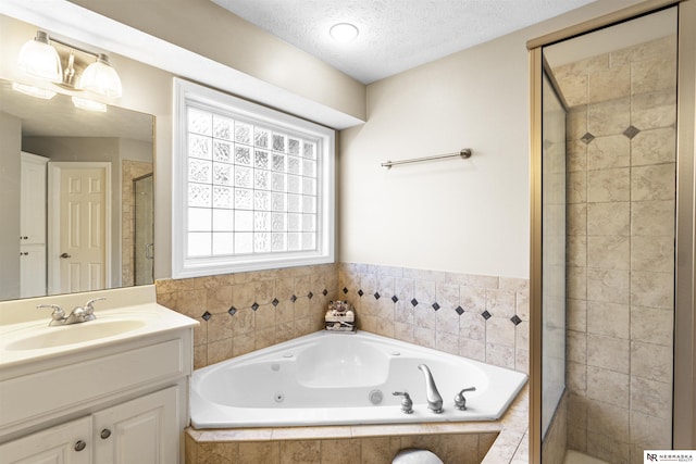 bathroom with vanity, a textured ceiling, a stall shower, and a whirlpool tub